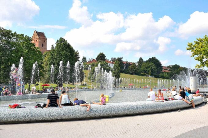 Multimedialny Park Fontann to jedno z najważniejszych miejsc na turystycznej mapie Warszawy. Ten niezwykły park, który łączy sztukę, technologię i wodę, został otwarty w 2011 roku i od tego czasu przyciąga rzesze turystów oraz mieszkańców stolicy. Położony jest na Skwerze 1 Dywizji Pancernej WP na Podzamczu, pomiędzy ulicami Boleść, Wybrzeże Gdańskie, Sanguszki i Rybaki na Nowym Mieście. W tym tekście przybliżymy Wam ciekawostki i zaskakujące fakty związane z tym wyjątkowym miejscem. Lokalizacja i otoczenie Multimedialny Park Fontann usytuowany jest u podnóża warszawskiej skarpy, co sprawia, że jest doskonałym punktem widokowym na Wisłę oraz panoramę Starego Miasta. W otoczeniu parku znajduje się wiele innych atrakcji turystycznych, takich jak Warszawska Strefa Rodziny, która oferuje spory plac zabaw dla dzieci. To sprawia, że jest to idealne miejsce na rodzinne spacery i spotkania z przyjaciółmi. Pokazy multimedialne Jednym z głównych powodów, dla których turyści odwiedzają park, są pokazy multimedialne. Odbywają się one codziennie, z wyjątkiem niedziel, a wieczorami w soboty prezentowane są spektakularne widowiska z muzyką, światłem i wodą. Efekty wizualne i dźwiękowe łączą się ze sobą, tworząc niezapomniane doświadczenia dla widzów. Fontanny i struktury wodne Park oferuje także liczne fontanny, które zachwycają nie tylko swoim wyglądem, ale również interaktywnością. Dzieci i dorośli mogą się bawić wodą, a zimą skarpa zamienia się w miejsce idealne do zjeżdżania na sankach. W sumie na terenie parku znajduje się dziewięć fontann, a największa z nich osiąga wysokość nawet 30 metrów. Impresjonistyczne inspiracje Multimedialny Park Fontann nie jest jedynym miejscem w Warszawie, gdzie sztuka łączy się z technologią. W stolicy odbyła się również multimedialna wystawa impresjonistów - Immersive Monet & The Impressionists. To pokazuje, że Warszawa to miasto, które łączy tradycję z nowoczesnością, co widać również w koncepcji parku fontann. Dostępność i parking Multimedialny Park Fontann jest łatwo dostępny zarówno dla turystów, jak i mieszkańców Warszawy. W pobliżu parku znajdują się parkingi, co ułatwia przyjazd samochodem. Ponadto, dzięki dogodnej lokalizacji, można tam dotrzeć również komunikacją miejską. Przyjazne dla środowiska Park Fontann został zaprojektowany z myślą o ekologii. Wodę, która jest wykorzystywana w trakcie pokazów, poddaje się procesowi recyrkulacji, dzięki czemu zużycie jest minimalne. To ważne z uwagi na rosnącą świadomość ekologiczną społeczeństwa oraz dbałość o zasoby naturalne. Przestrzeń dla kreatywności Park Fontann to nie tylko miejsce do wypoczynku i relaksu, ale także przestrzeń dla artystów. W ramach imprez kulturalnych odbywają się tu występy, koncerty czy spektakle teatralne. Jest to więc miejsce, gdzie można doświadczyć różnorodnych form sztuki. Integracja z otoczeniem Multimedialny Park Fontann został zaprojektowany tak, aby wpisywać się w istniejący krajobraz miasta. Starannie dobrana roślinność, układ przestrzenny oraz materiały użyte do budowy parku sprawiają, że stanowi on harmonijną część warszawskiego Nowego Miasta.