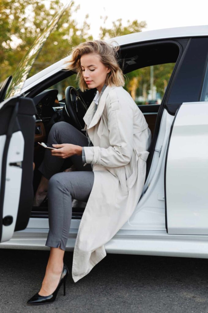 piękna kobieta siedząca w samochodzie i korzystająca z telefonu