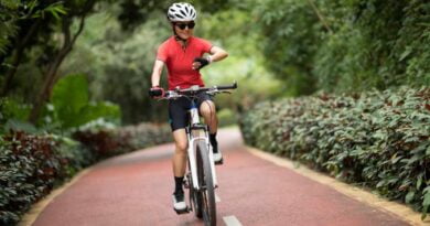 Kobieta rowerzystka patrząca na swój smartwatch podczas jazdy rowerem na świeżym powietrzu w słoneczny dzień