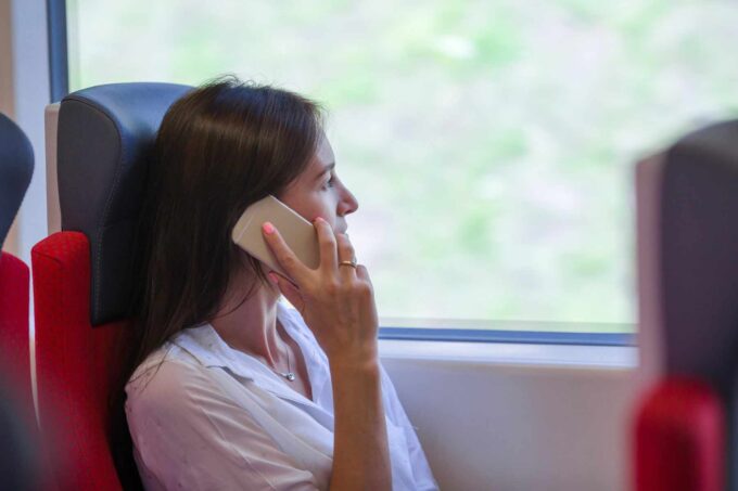 Młoda kobieta rozmawiająca przez telefon, jadąca pociągiem