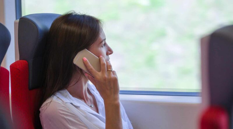 Młoda kobieta rozmawiająca przez telefon, jadąca pociągiem