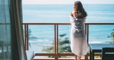 Piękna kobieta stoi i cieszy się widokiem morza stojąc na balkonie