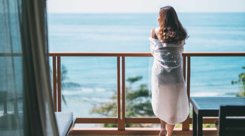 Piękna kobieta stoi i cieszy się widokiem morza stojąc na balkonie