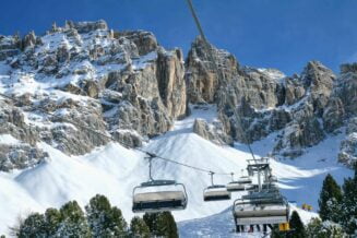 Jazda na nartach w Dolomitach, kabiny dla narciarzy nad horyzontem na tle góry