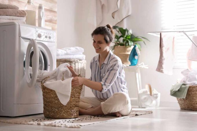 Młoda kobieta wyjmująca pranie z pralki w domu