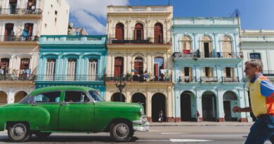 Zielony zabytkowy samochód i pan przechodzący przez ulicę w Hawanie