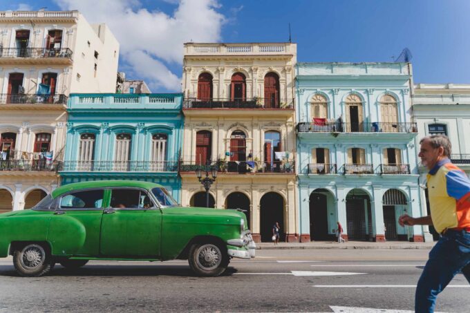 Zielony zabytkowy samochód i pan przechodzący przez ulicę w Hawanie